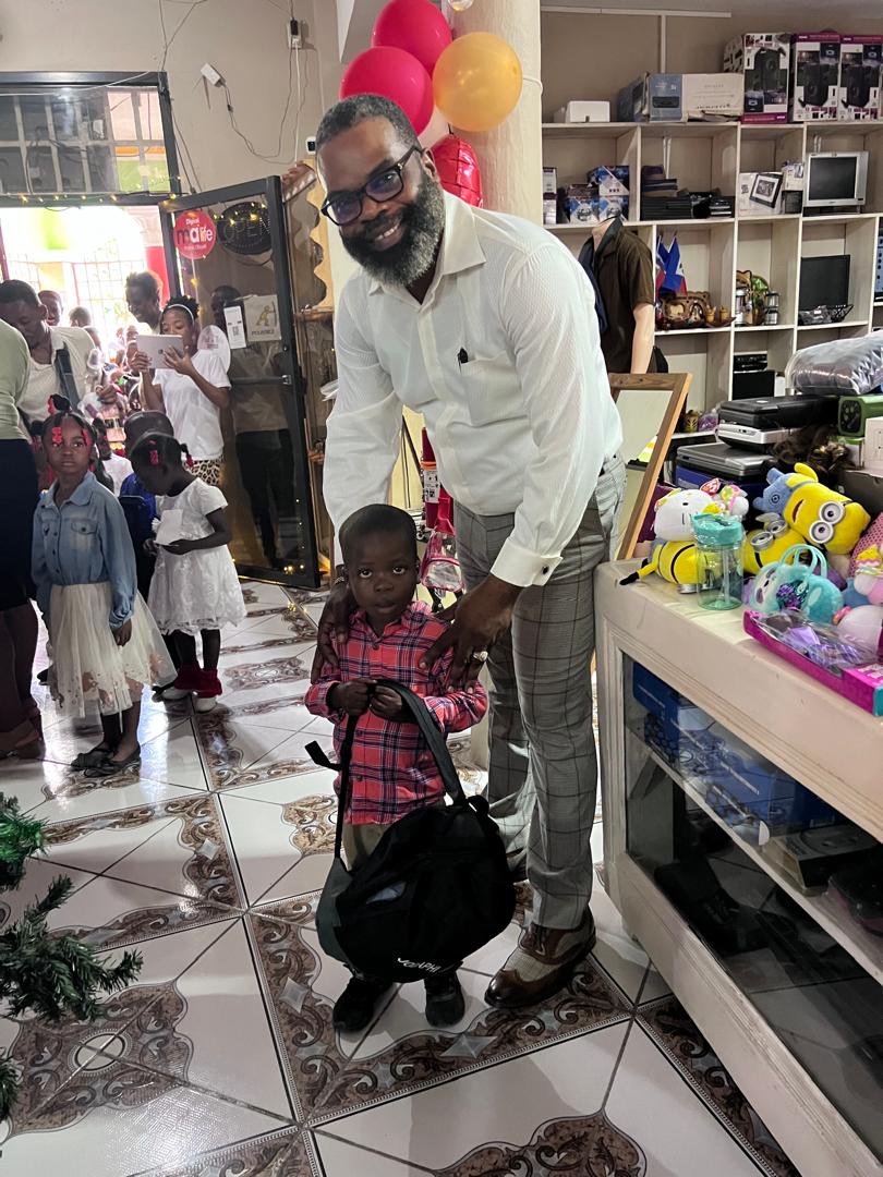 Pastor presenting a backpack to a young child at the Christmas distribution
