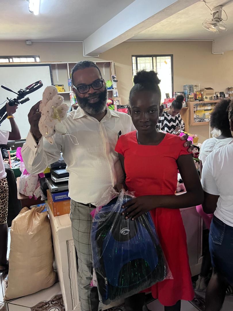 Girl receiving a backpack and small toy from the pastor