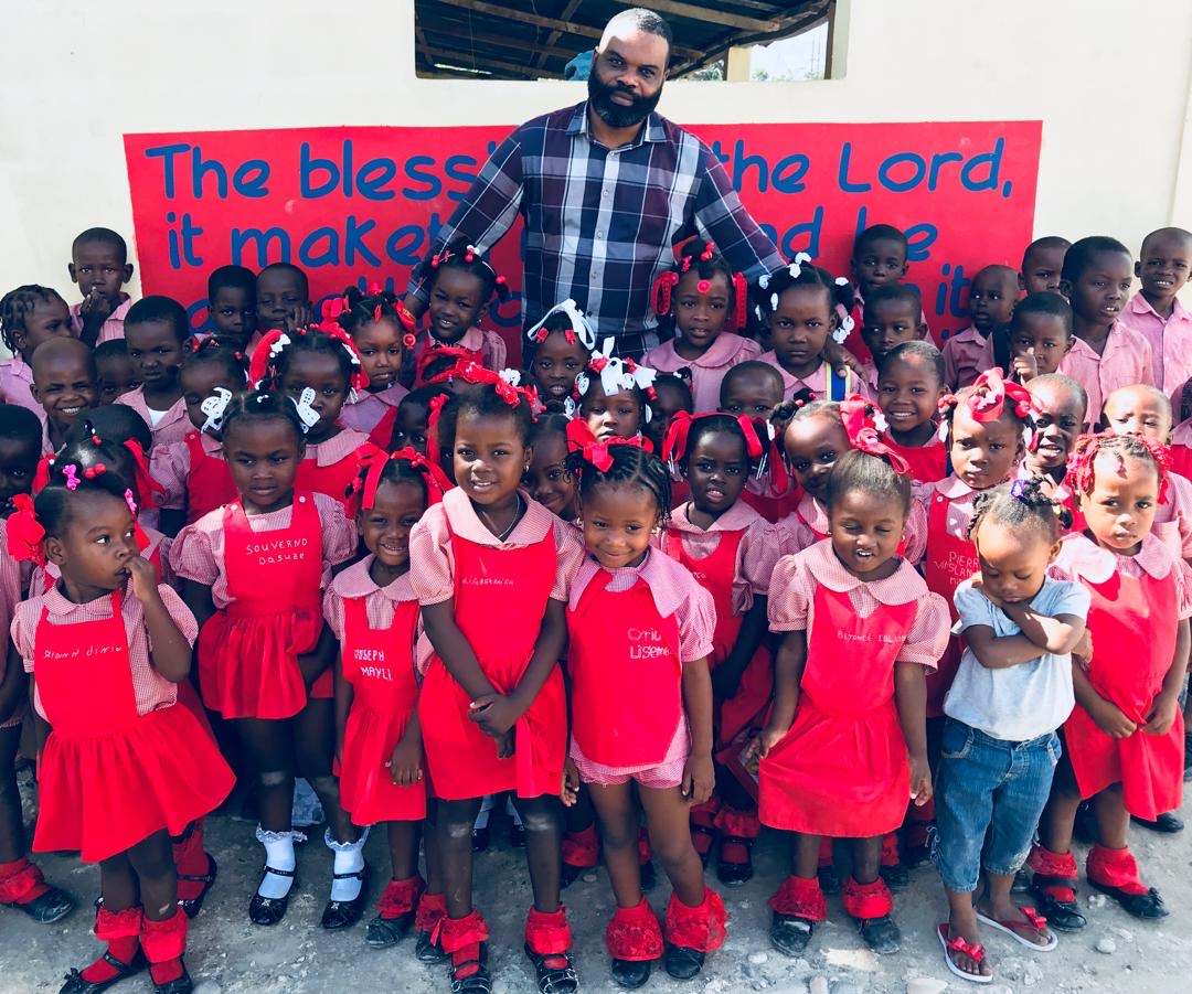 Pastor with kindergarten class in front of a Scripture mural